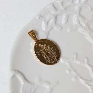 Detailed view of an oval 18K gold-plated religious pendant with Virgin Mary engraving