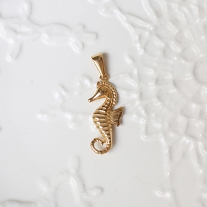 Detailed close-up of a 18K gold-plated seahorse pendant with polished finish details