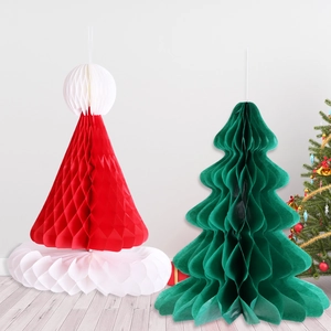 Close-up of honeycomb paper Christmas tree and Santa hat decorations on wooden floor