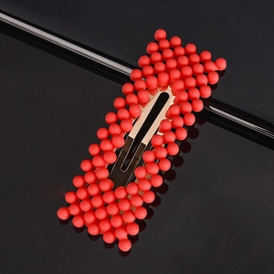 Detailed view of sweet red bead hair clip with golden metal base on black background