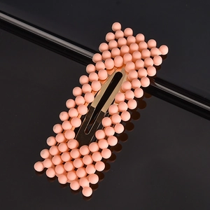 Detailed close-up of peach-colored beaded hair clip on a premium gold-tone metal base
