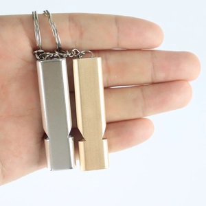 Close-up of gold and silver aluminum dual-frequency survival whistles with keychains