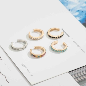 Detailed flat lay of diverse U-shaped ear cuffs with colorful rhinestones in gold and silver