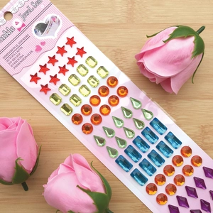 Close-up of colorful acrylic jewel stickers in star and drop shapes on pink card