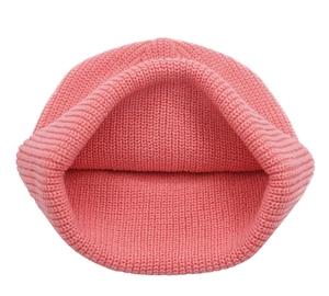 Detail of pink knitted beanie showing ribbed texture and interior dome construction
