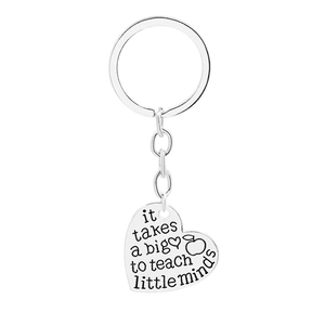 Close-up of heart-shaped keychain engraved with inspirational quote for teachers