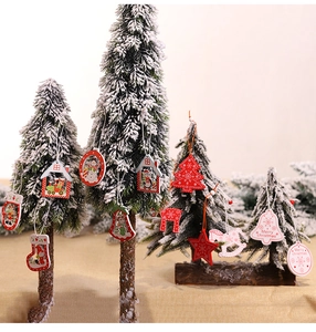 Close-up of red and white Christmas wooden ornaments hanging on a snowy Xmas tree