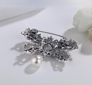 Close-up of vintage silver bow brooch with white pearl drop and pin closure detail