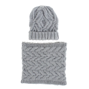 Detail view of light grey winter knitted hat and neck gaiter with thick cable knit texture