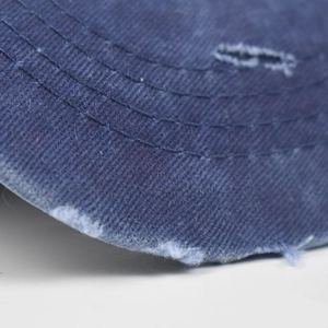 Close-up of navy washed denim baseball cap featuring distressed edges and parallel stitching