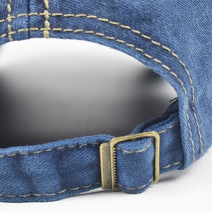 Detail of blue denim baseball cap with vintage metal buckle and yellow contrast stitching