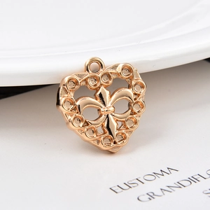 Macro shot of gold brass heart charm featuring fleur-de-lis and hollow circle details