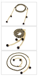 Detail of gold metal chain woven with black leather and elegant beaded tassel charms