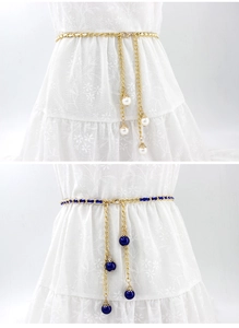 Detail of metal chain waist belt with white and royal blue pearls on a lace dress