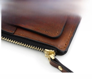 Close-up of golden metal zipper and brown lychee grain leather on a sleek lady wallet