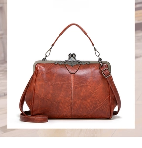 Close-up of vintage reddish-brown PU leather handbag with carved metal frame and clasp