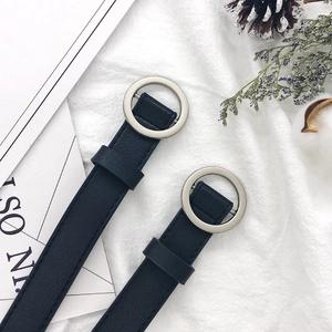 Minimalist black PU leather belts with silver round buckles on decorative background
