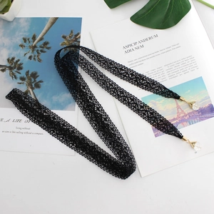 Elegant black lace waist rope with gold metal tips and crystal pendants on a white table