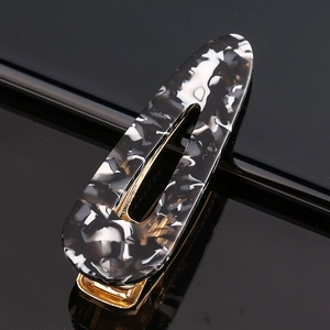 Macro view of marbled acetate hair clip with golden metal base and oval cut-out design