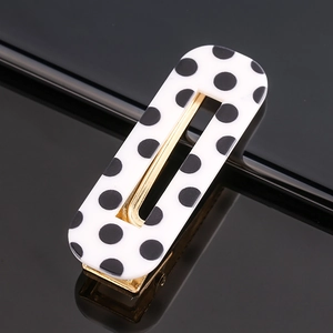 Detail view of the black polka dot acetate hair clip with a gold metallic frame