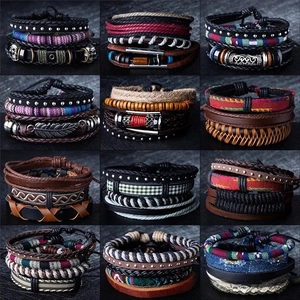 Detail view of 12 multi-layer leather bracelets with punk charms like feathers and anchors