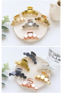 Detail showing minimalist circular metal hair claws in various metallic finishes on a tray