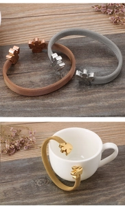 Close-up of mesh weave cuff bracelet featuring teddy bear charm in gold and silver finish
