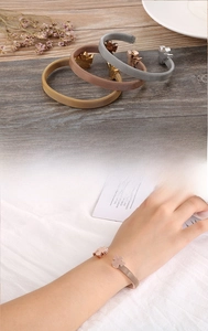 Three-color mesh woven stainless steel bracelets with flower charms on wooden table