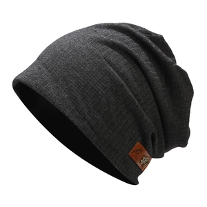 Détail d'un bonnet en maille gris foncé avec écusson en cuir brun et texture gaufre