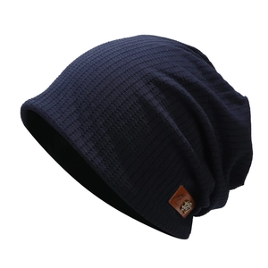 Détail d'un bonnet en maille bleu marine avec un écusson en cuir marron et texture tricotée