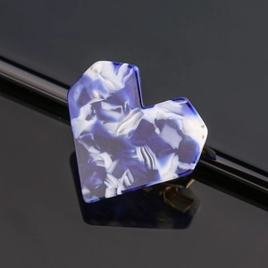 Close-up of heart-shaped blue and white marble pattern acrylic hair clip on black base