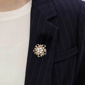 Detail of vintage flower brooch with white pearls and gold metal on navy blazer lapel