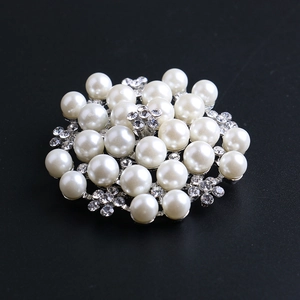 Macro shot of elegant silver flower brooch with white pearls and sparkling rhinestones