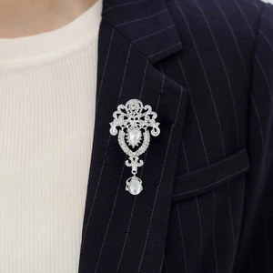 Macro shot of silver vintage brooch with pear-shaped crystal pendant on a navy striped blazer