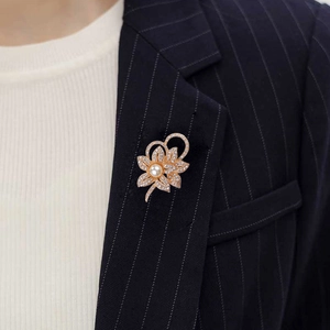 Detail view of crystal flower brooch with white pearl on a dark navy suit lapel