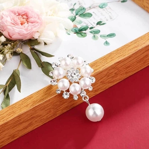 Macro detail of floral pearl brooch featuring sparkling rhinestones and a teardrop pendant