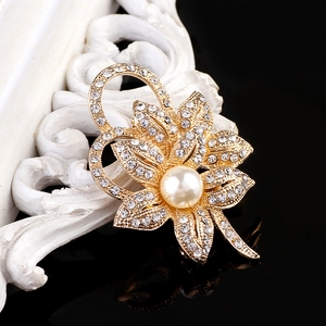 Close-up of elegant gold flower brooch with sparkling crystals and a large white pearl