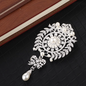 Detailed view of silver flower brooch with large pearl, rhinestones and tassel drop