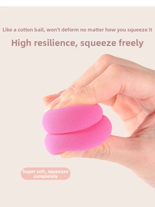 Close-up of bright pink makeup sponge being squeezed to show high elasticity and soft texture