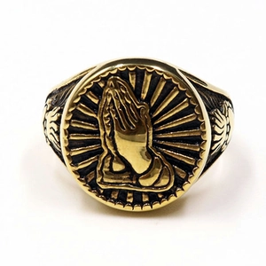 Macro detail of vintage gold praying hands relief on a religious envelope ring