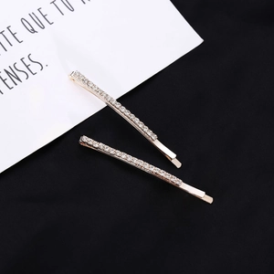 Detail view of a two-piece rose gold rhinestone hair clip set on a black background