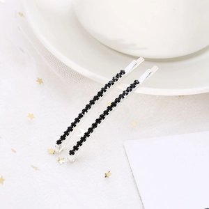 Silver metal hair clips set with sparkling black rhinestones on star pattern background