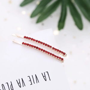 Macro shot of a pair of gold hairpins set with a single row of sparkling red rhinestones