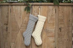 Gestrickte Weihnachtssocken mit Rautenmuster an einem rustikalen Holzschrank aufgehängt