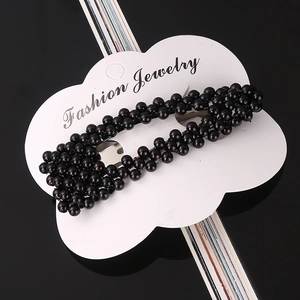 Detail of hand-woven black pearl hair clip on white fashion jewelry card display
