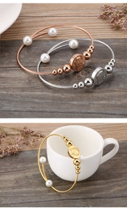 Detailed view of woven wire bracelets with pearls and religious relief pendants