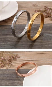 Detailed view of gold and silver bangles with square crystals on a wooden surface
