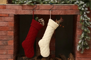 Detail of red and cream knitted Christmas stockings with cable pattern hanging on a fireplace