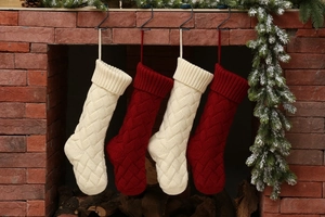 Classic red and white cable-knit Christmas stockings hung on a festive brick fireplace