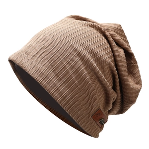 Dettaglio del berretto in maglia marrone con trama a righe e patch logo in pelle